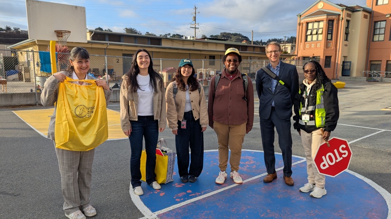 People standing for photo, one with a yellow Vision Zero cape