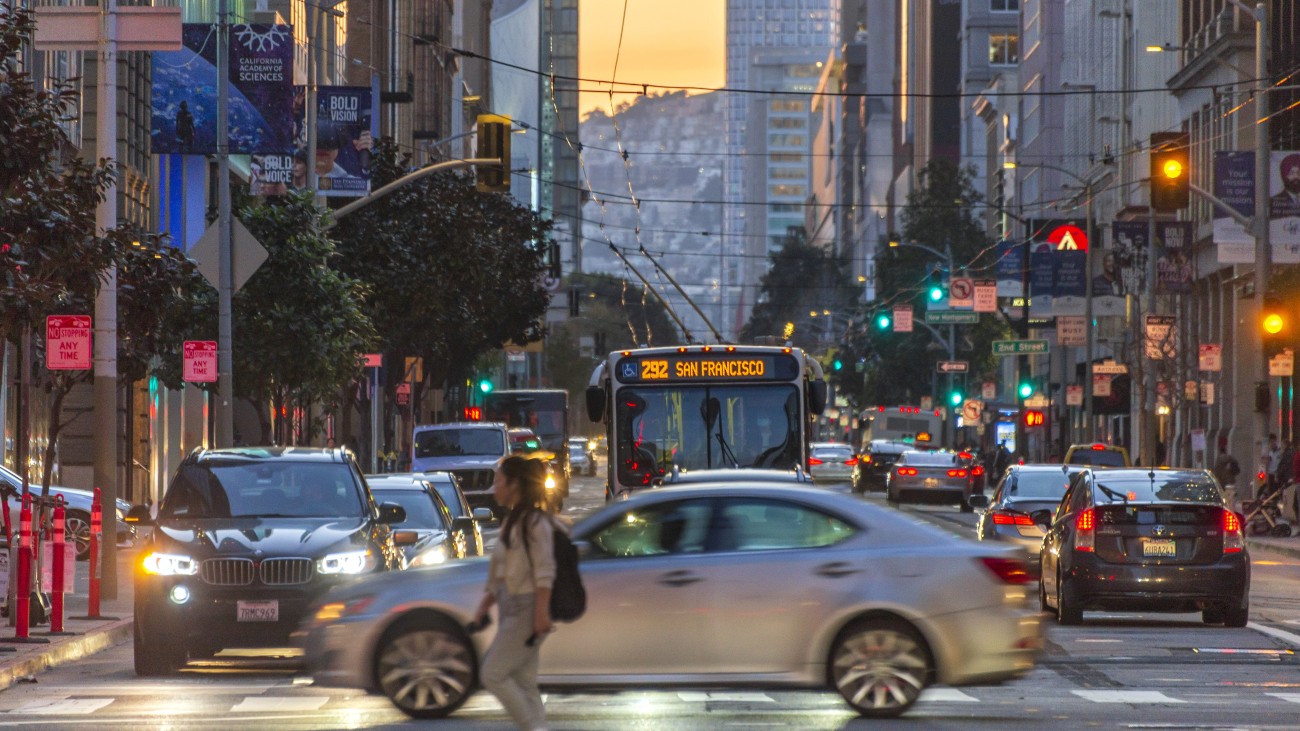 A pedestrian, vehicles, and transit along Mission Street