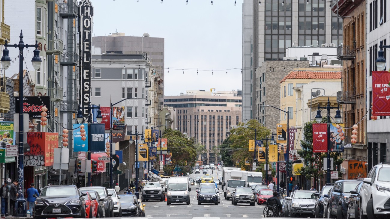 View Larkin Street, with vehicles parked along the side, businesses, and vehicles on the road