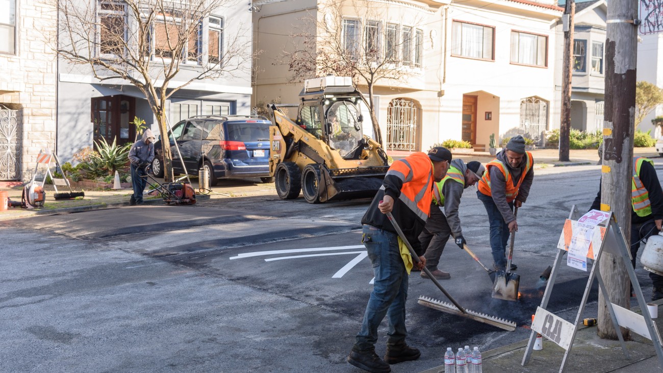Workers raking material to create a traffic calming speed hump