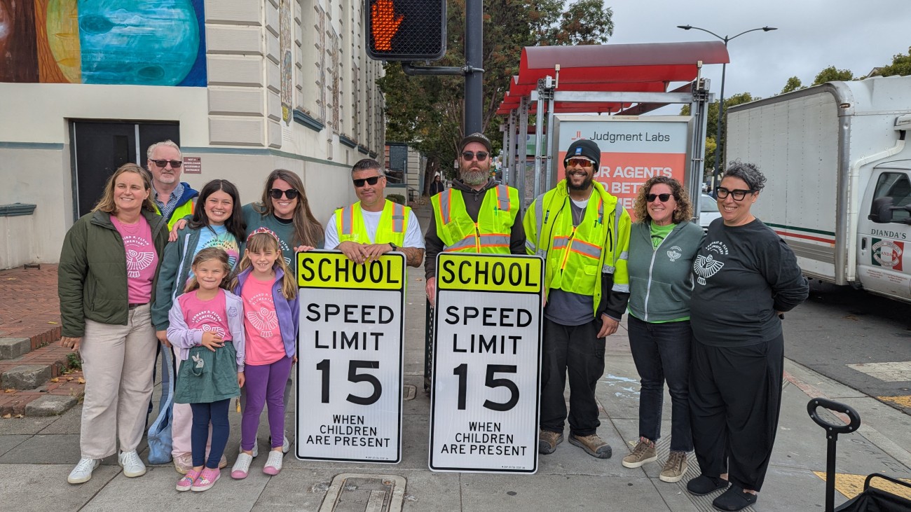 A group gathering around new street safety signs in front of a school 