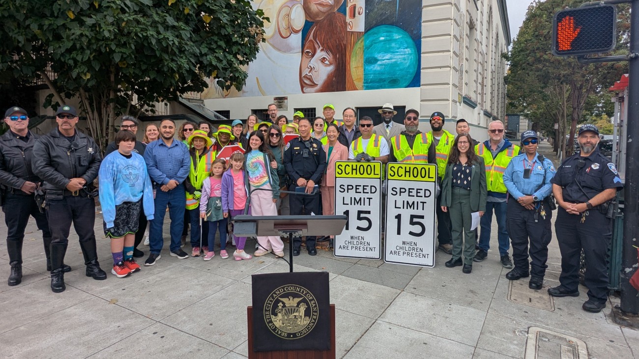 A big community group standing in front of a school 