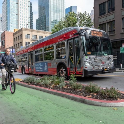 Man riding a bike next to a bus