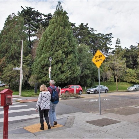 people walking across a street with speed bumps