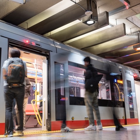 Muni metro train with motion blur of people exiting the train and people waiting on platform
