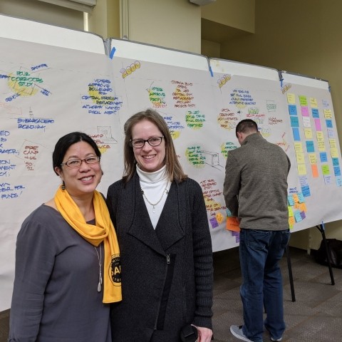 Tilly Chang and Maria Lombardo standing in front of wall of writing