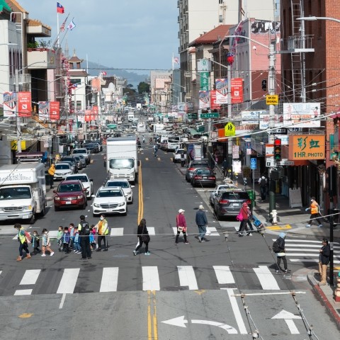 View of the Sacramento and Stockton Street intersection in Chinatown with pedestrians, trucks, and cars.