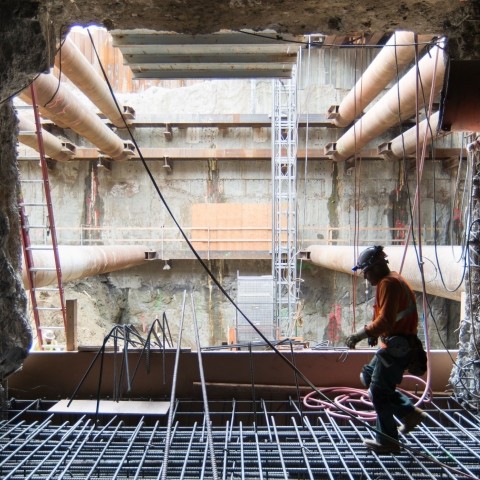 Backlit photo of a construction worker stepping across a rebar cage.