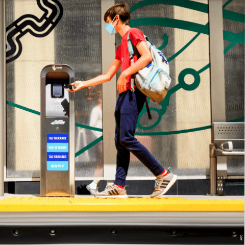 Student swiping Clipper card on platform. 