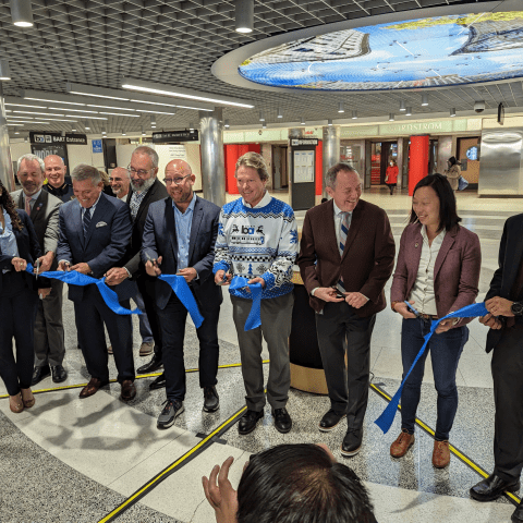 City and transportation officials cutting a blue ribbon at Powell Station