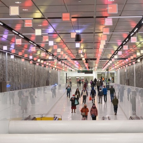 People walking in Central Subway, illuminated decorations hang from ceiling