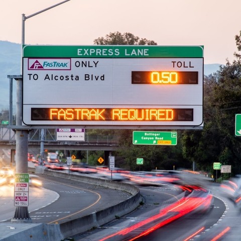 Express lane freeway signage with blurred vehicle lights on the road below it