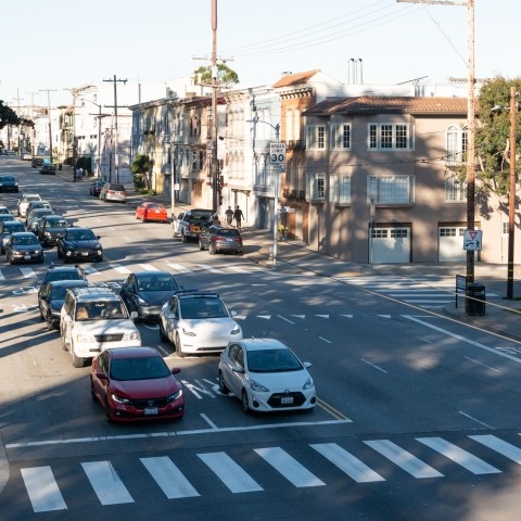 Vehicles stopped by traffic light on road along Fulton Street