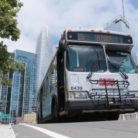 The 25 Muni bus which serves Treasure Island on the road with Salesforce building and other buildings visible in background
