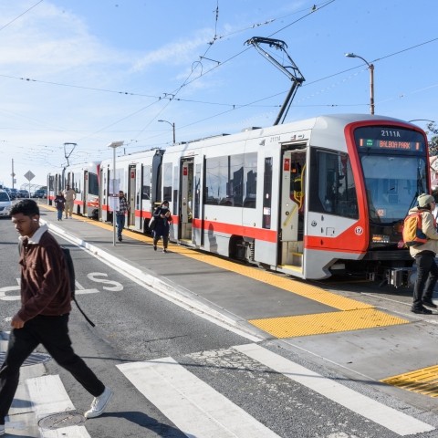 Muni M at platform with pedestrians crossing