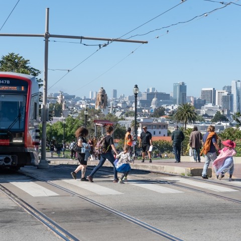 People Crossing in Front of J Church Train at Dolores Park
