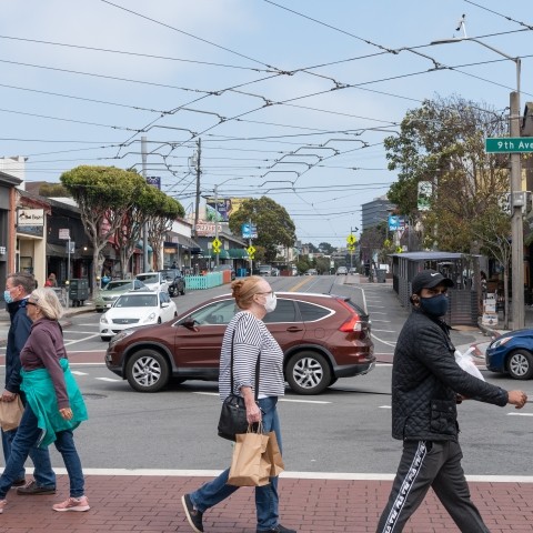 Pedestrians walking across the street at 8th and Irving 