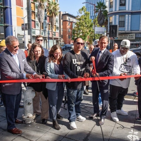 City officials, transportation officials, and community leaders cutting a red ribbon