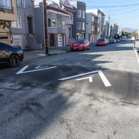 Speed hump with arrows and cars parked against the curb. 