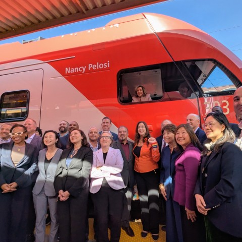 Speaker Emerita Pelosi in pilot with group of electeds in front of train