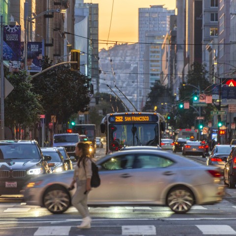 A pedestrian, vehicles, and transit along Mission Street