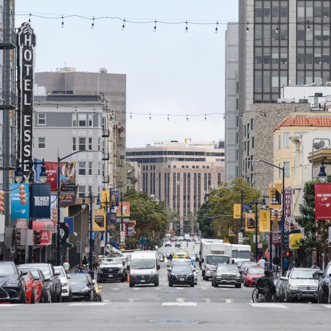 View Larkin Street, with vehicles parked along the side, businesses, and vehicles on the road
