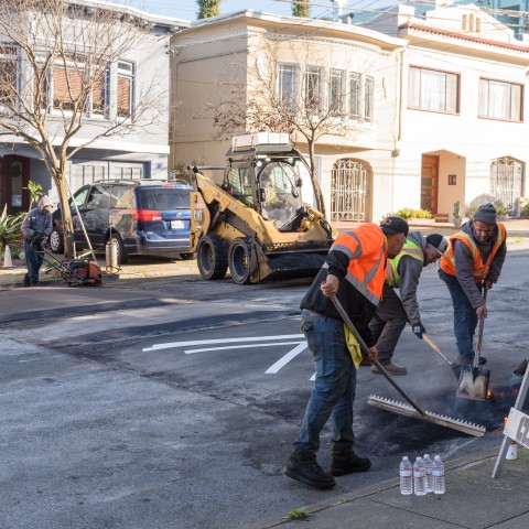 Workers raking material to create a traffic calming speed hump