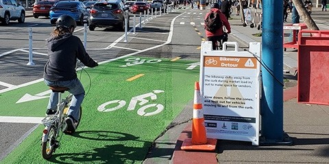 People ride bicycles in a two-way cycletrack on the Embarcadero.