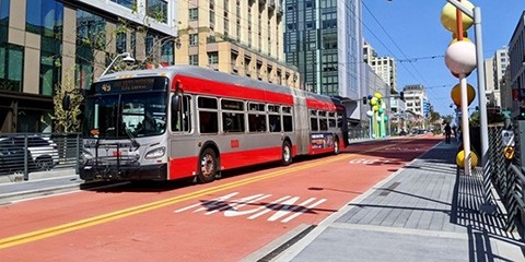 A 49 Van Ness Muni bus in a red-painted bus-only lane at a station.