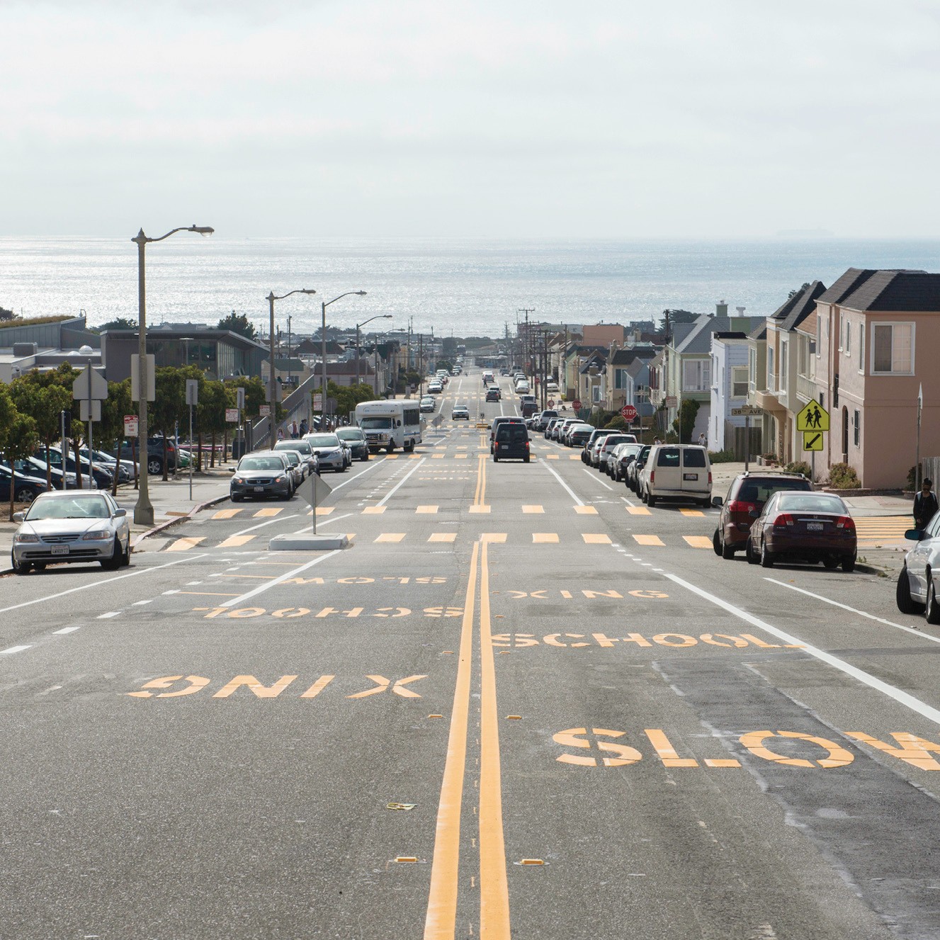 Ortega Street looking west toward the Pacific Ocean. "Slow school xing" is stenciled in yellow letters on the pavement. 